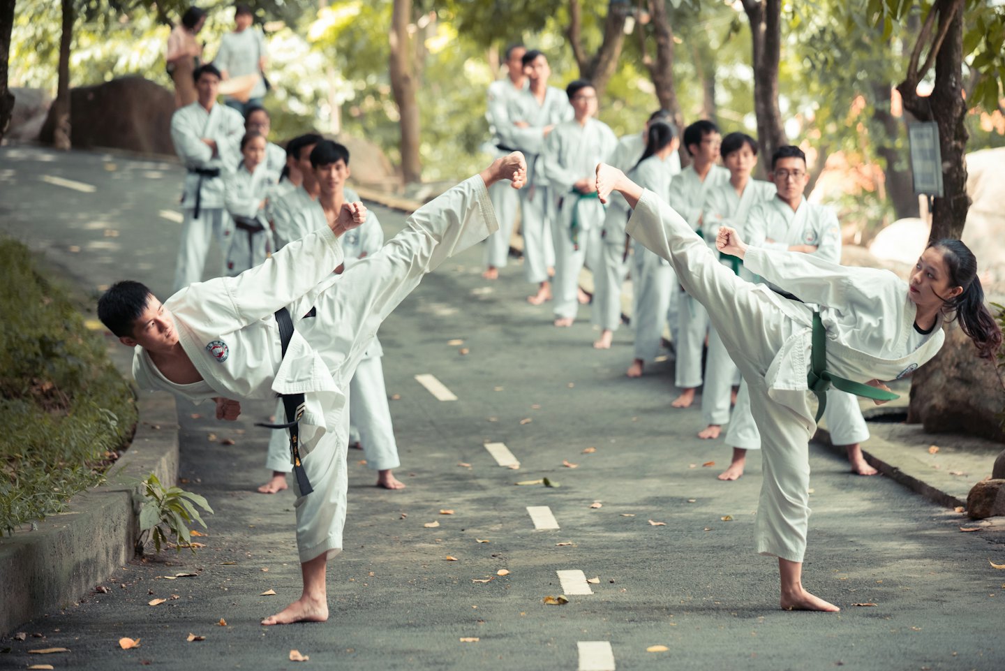 Two martial arts students practice synchronized high kicks.