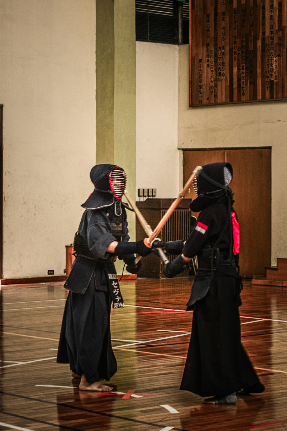 Two kendo practitioners sparring with bamboo swords in a dojo.