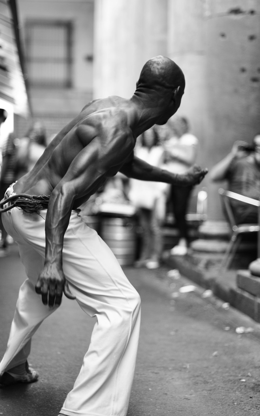 Man in light pants striking a martial arts pose on a street.